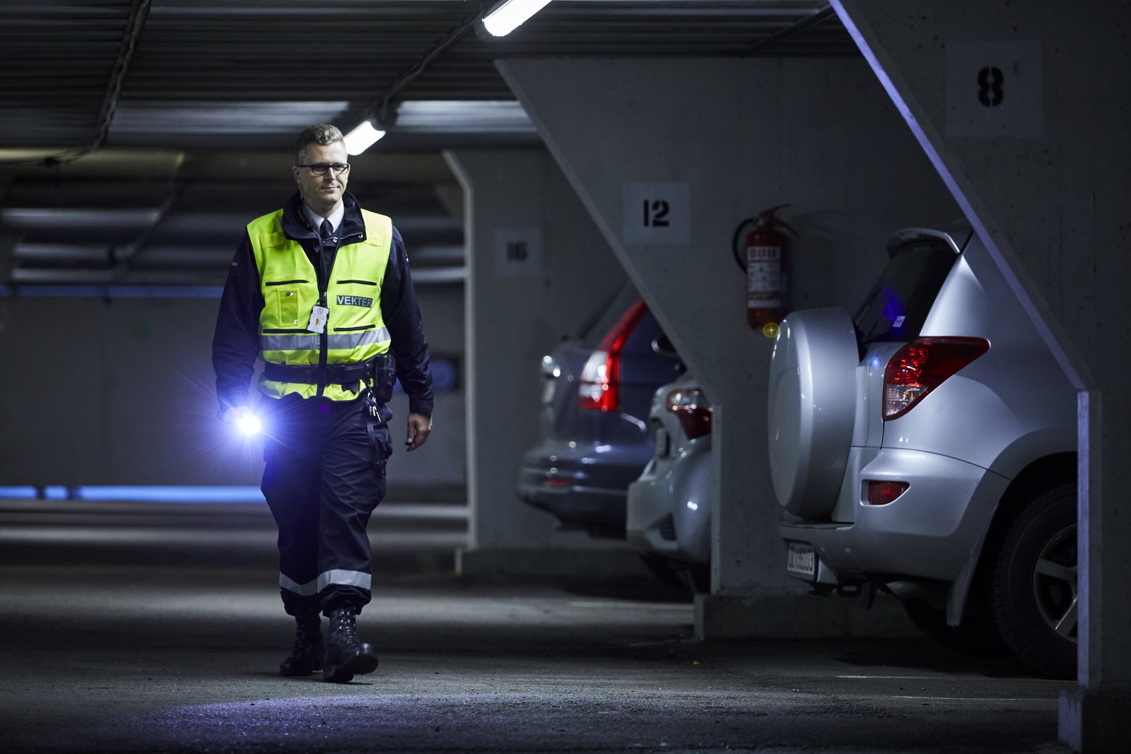 Vekter fra Sikkerhetsgruppen kontrollerer en parkeringsgarasje med lommelykt